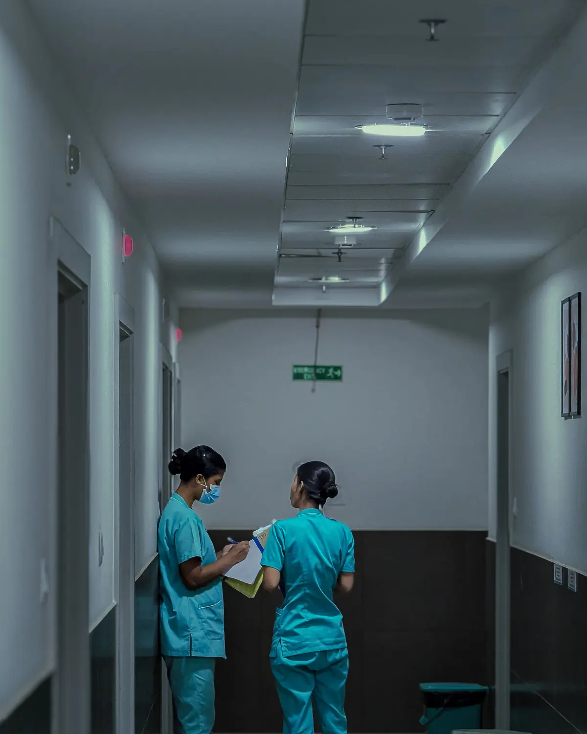 Two nurses reviewing notes together in a hospital corridor